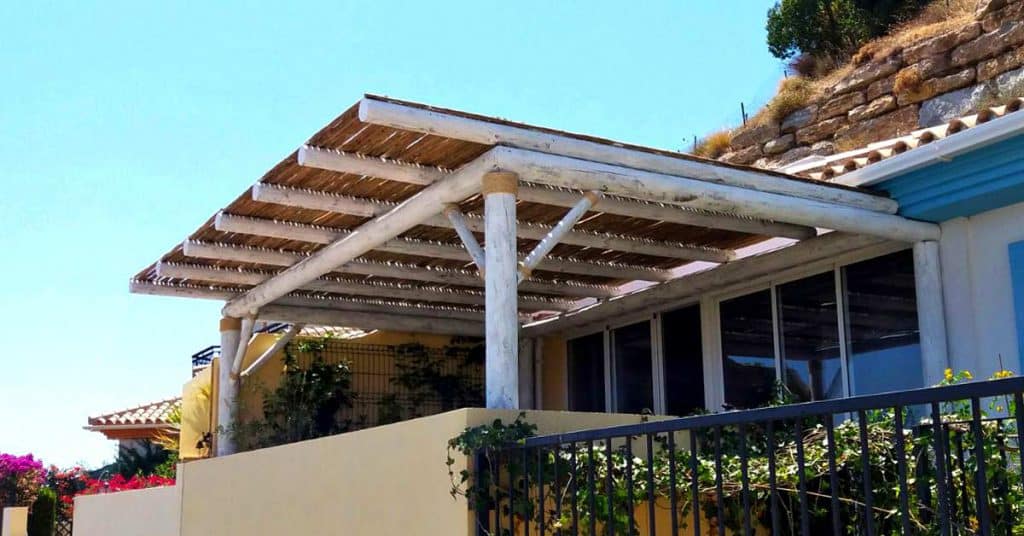 Compact wooden pergola installed on a Spanish apartment balcony creating shaded seating area