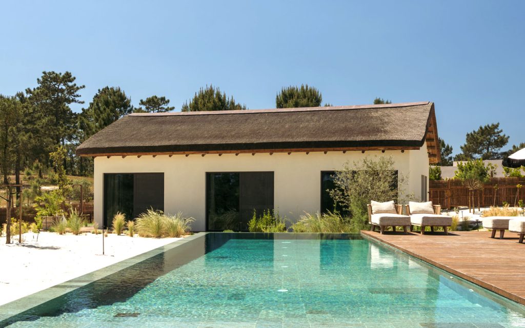 Cape Reed thatched pool house with timber decking and infinity pool at Villa Stark, Comporta